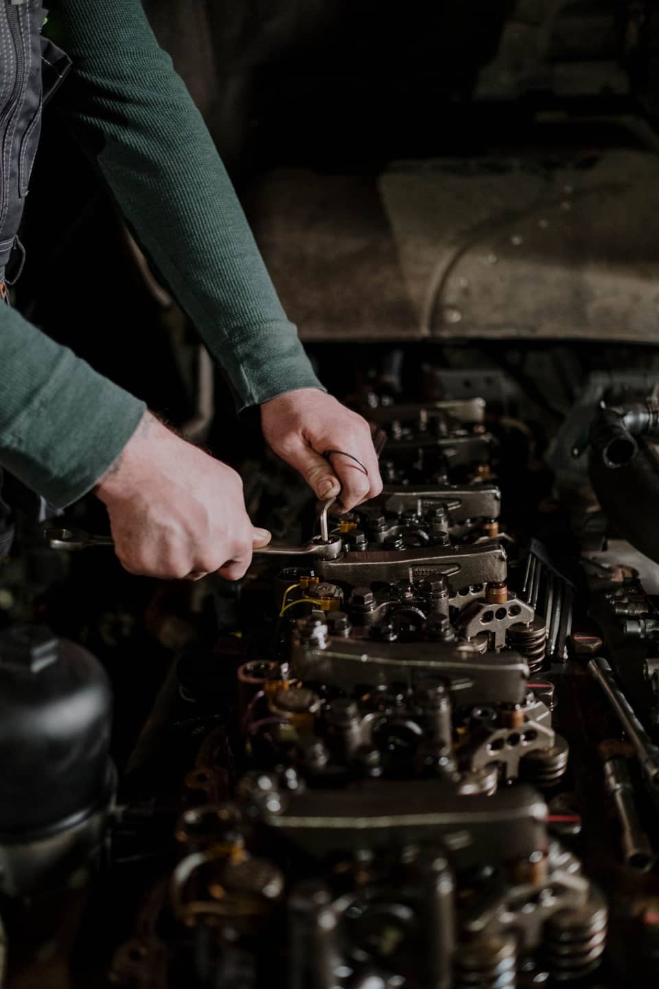 A mechanic's hands torquing the rocker assembly of a diesel engine